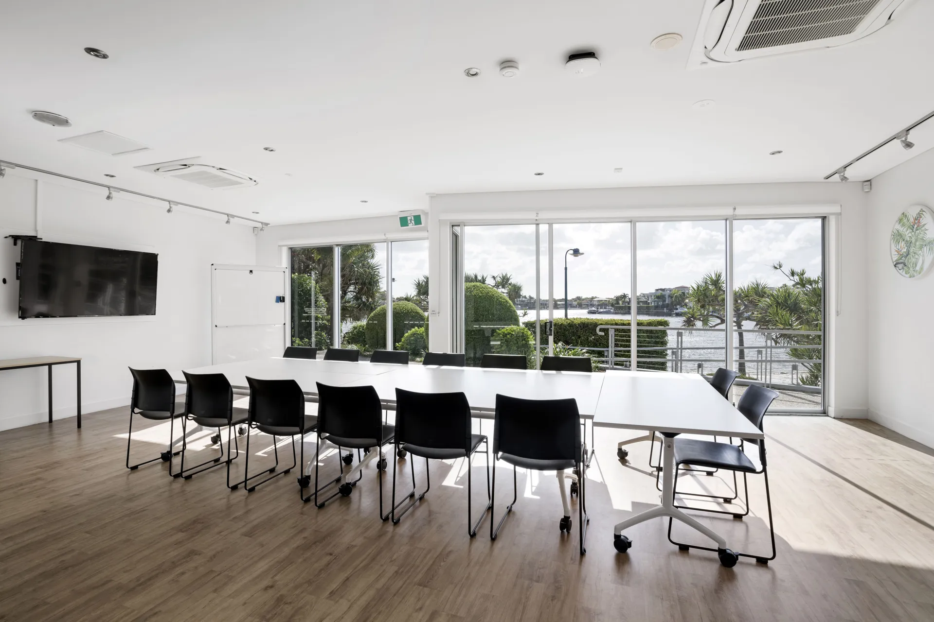 Indoor community meeting room with TV screen, desks and view of water