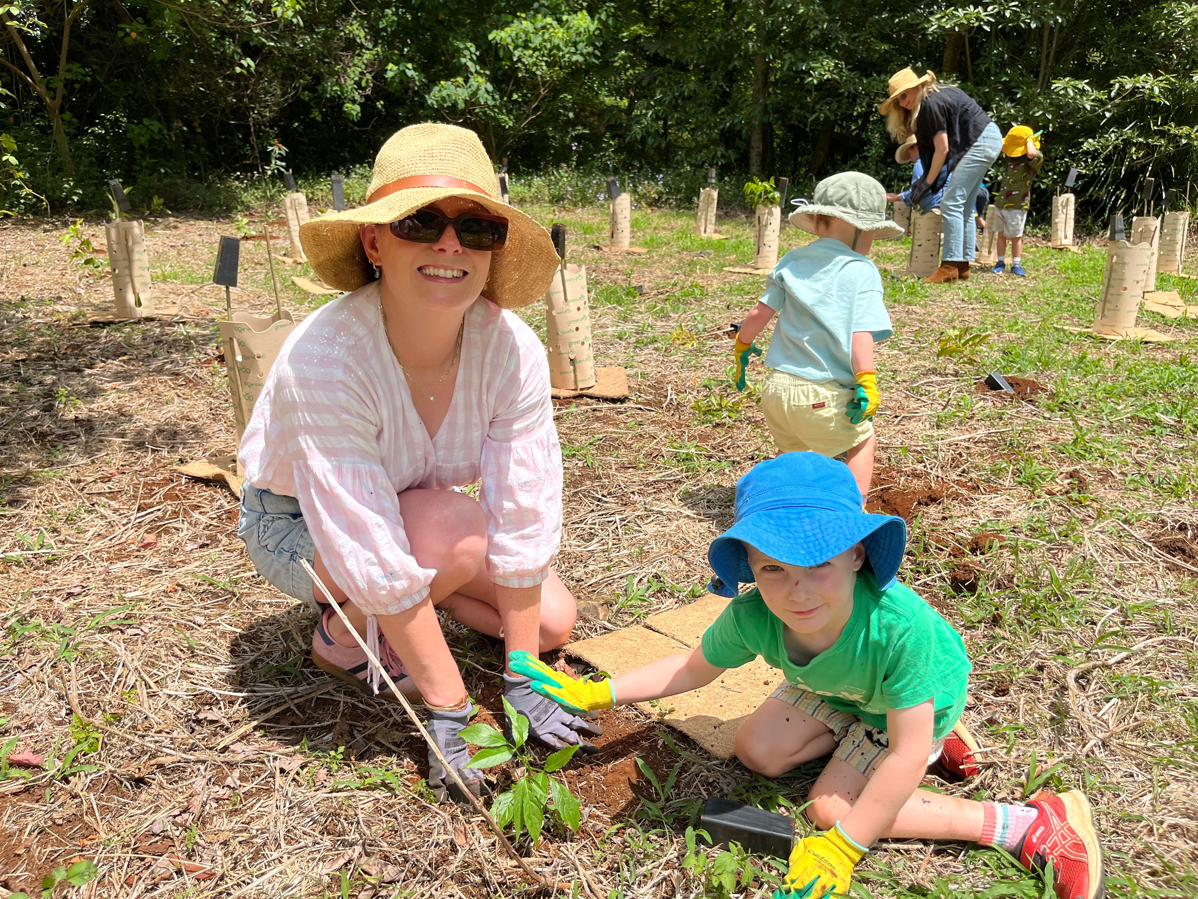 A woman and boy plant a seedling.