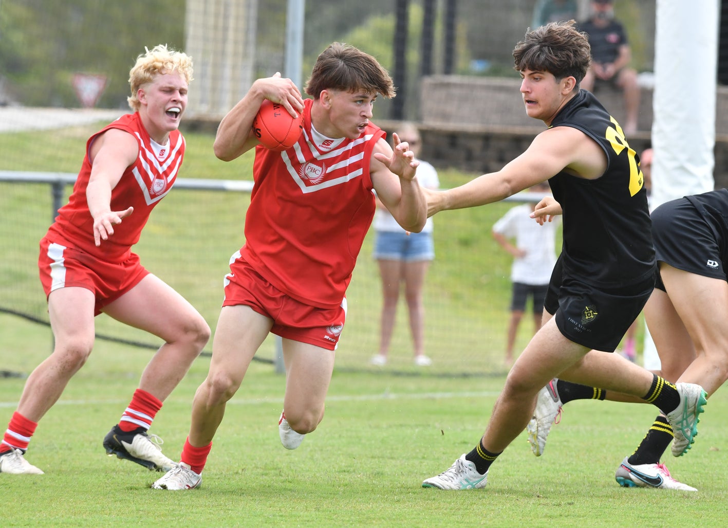 Three AFL players on field and in motion.