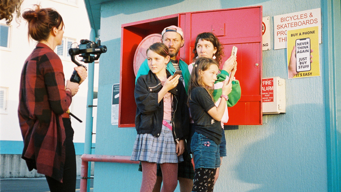 RADF Project. Photographer takes a portrait of two adults and two children against a building