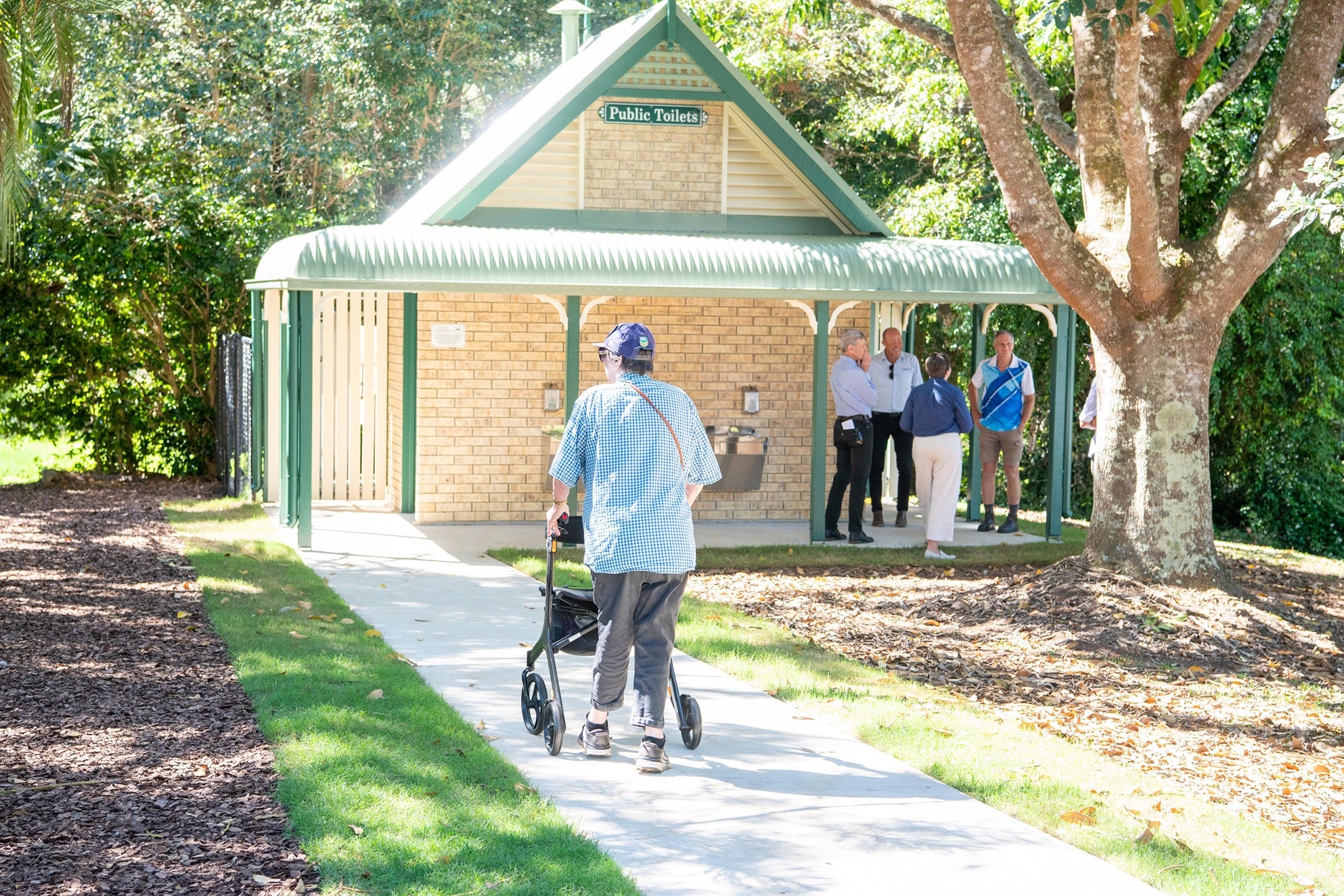 A woman with a mobility device using the new accessible pathway at Mapleton Lilyponds Park.