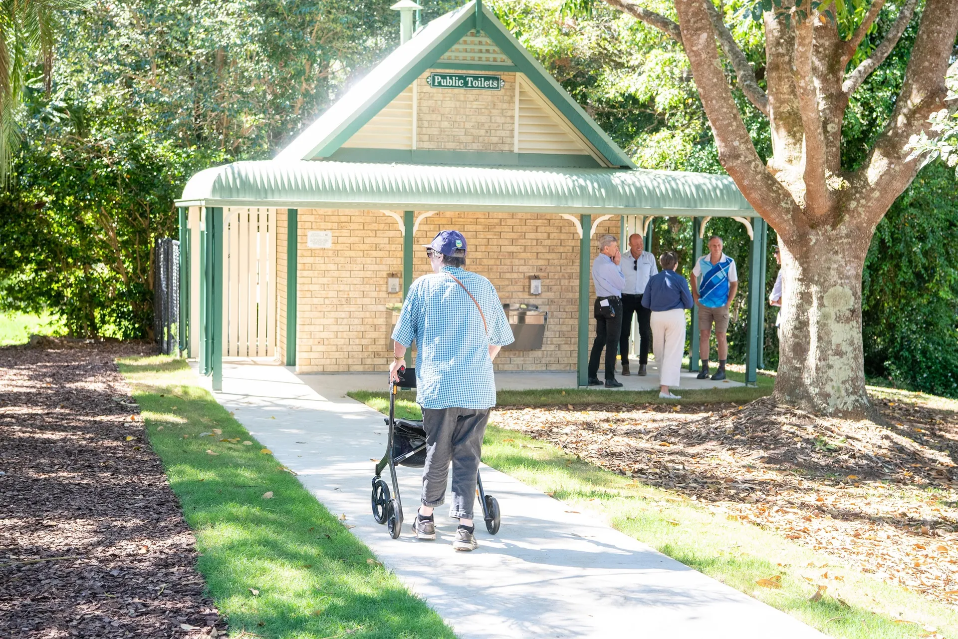 A woman with a mobility device using the new accessible pathway at Mapleton Lilyponds Park.