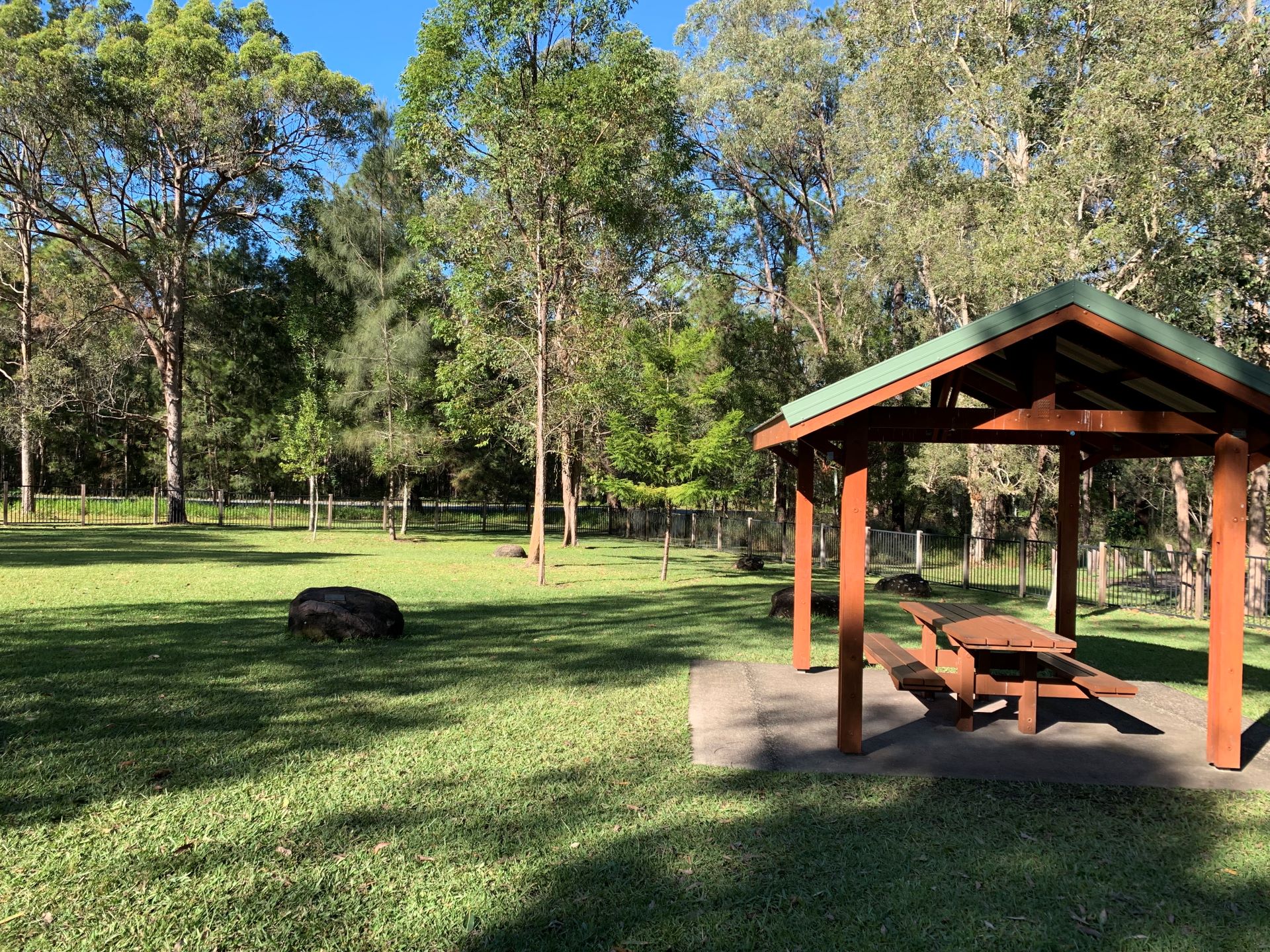Fenced playground area with picnic tables and shelter