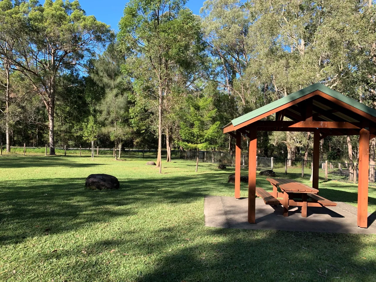 Fenced playground area with picnic tables and shelter