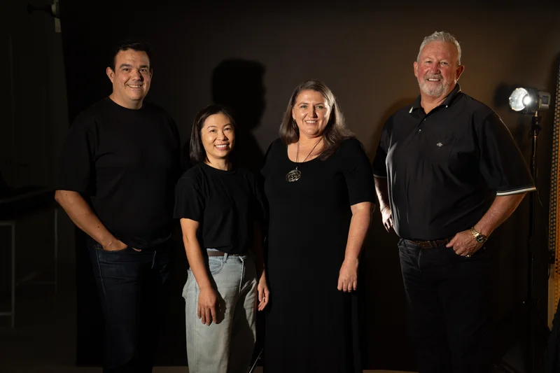 Four Shine a Light on Racism campaign patrons stand together wearing black with a golden light shining brightly behind them to help shine a light on racism. 