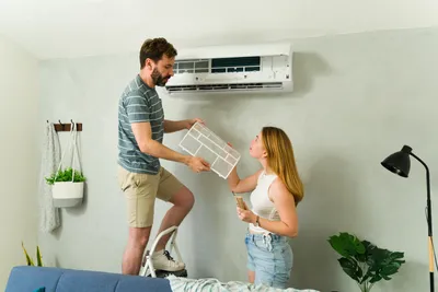 Couple removing air conditioning filters ready to clean