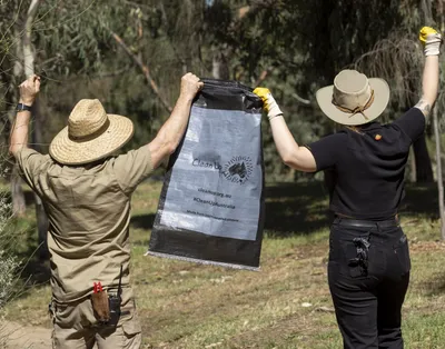two clean up volunteers holding an empty clean up bag