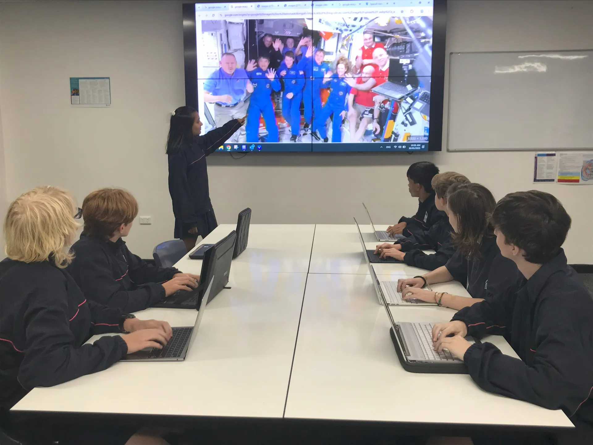 Students looking at a tv screen with astronauts communicating to them.