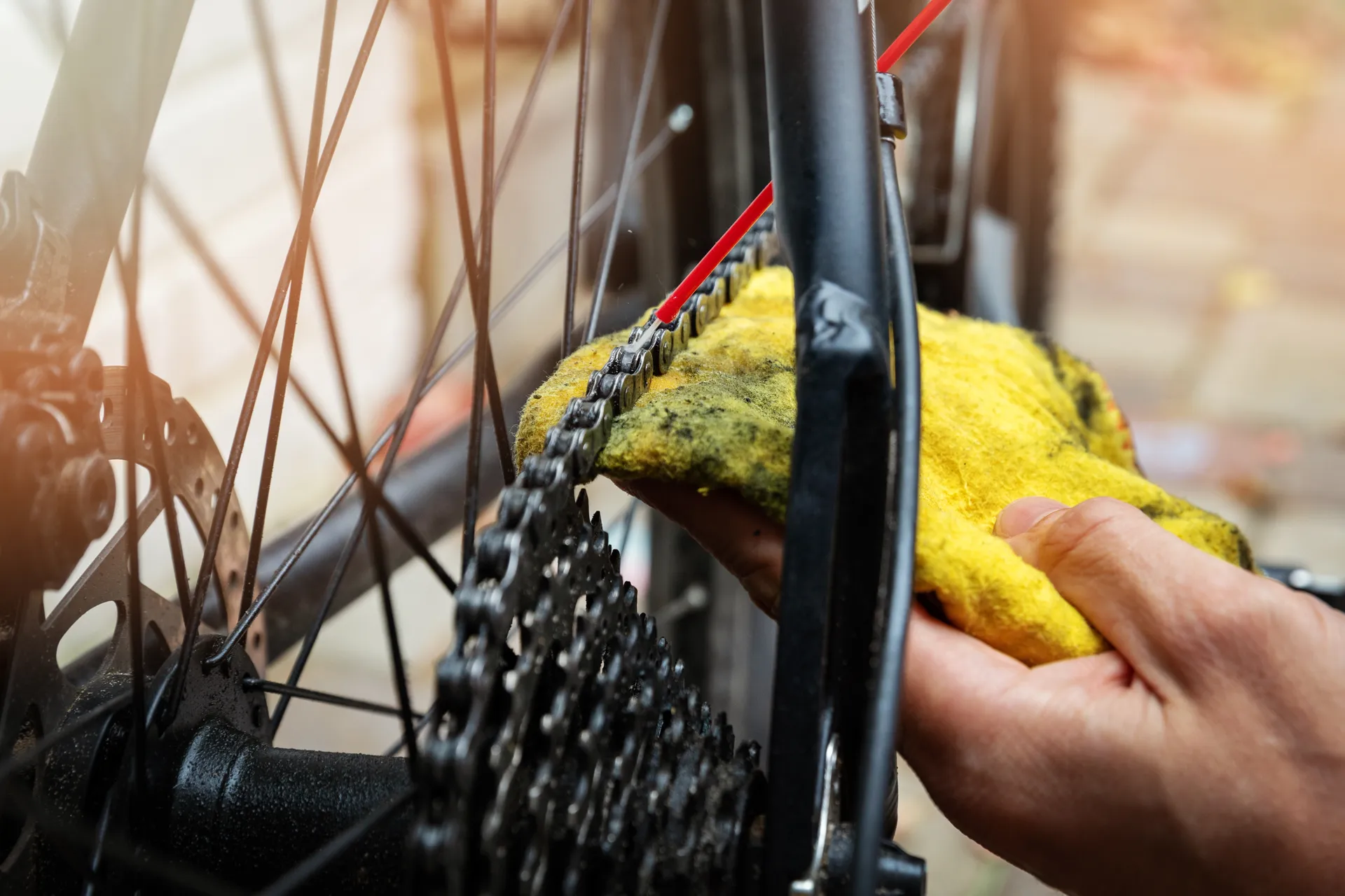 a hand with a cloth, cleaning a bike chain