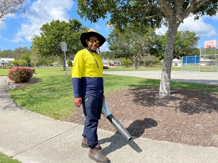 Young man wearing PPE performing outdoor garden maintenance 