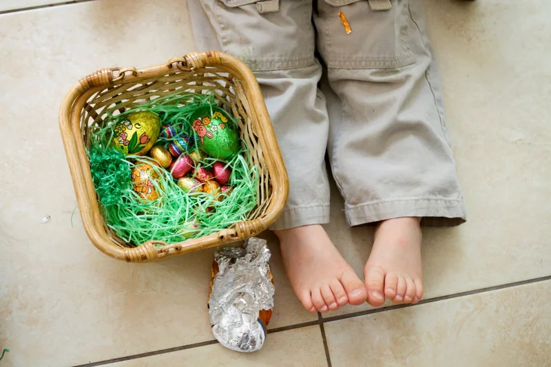 young child sitting with a basket of easter eggs