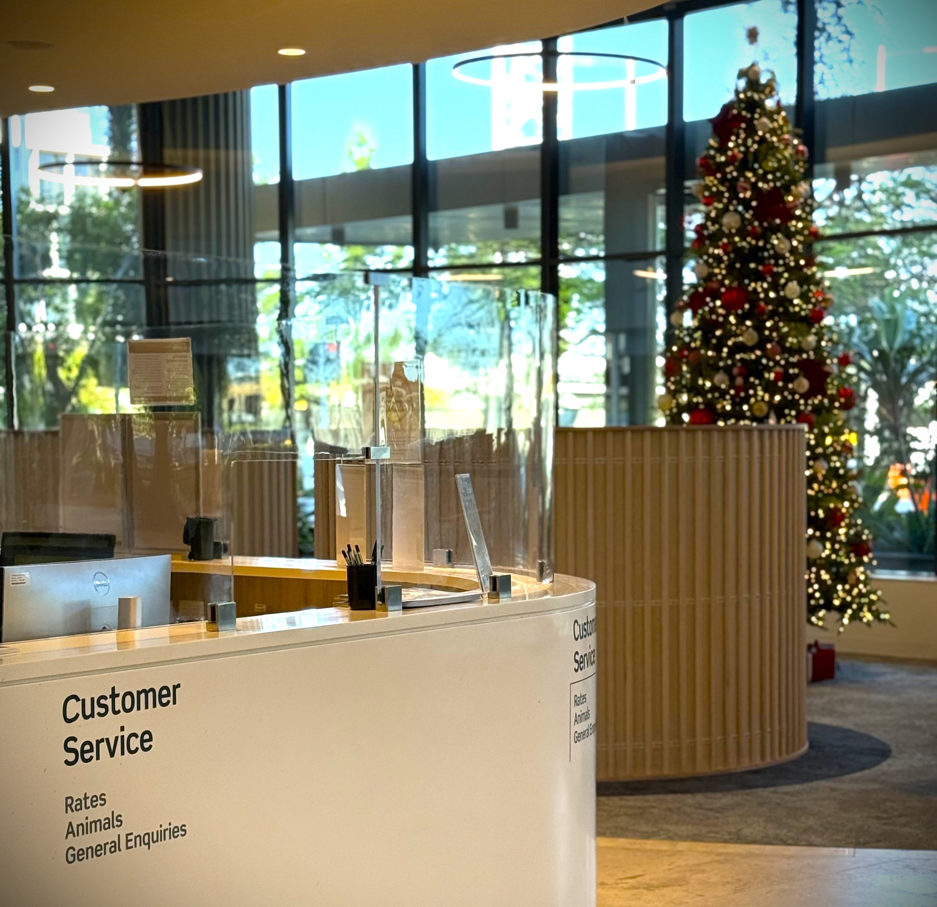 Behind the City Hall customer service counter stands a large Christmas tree.