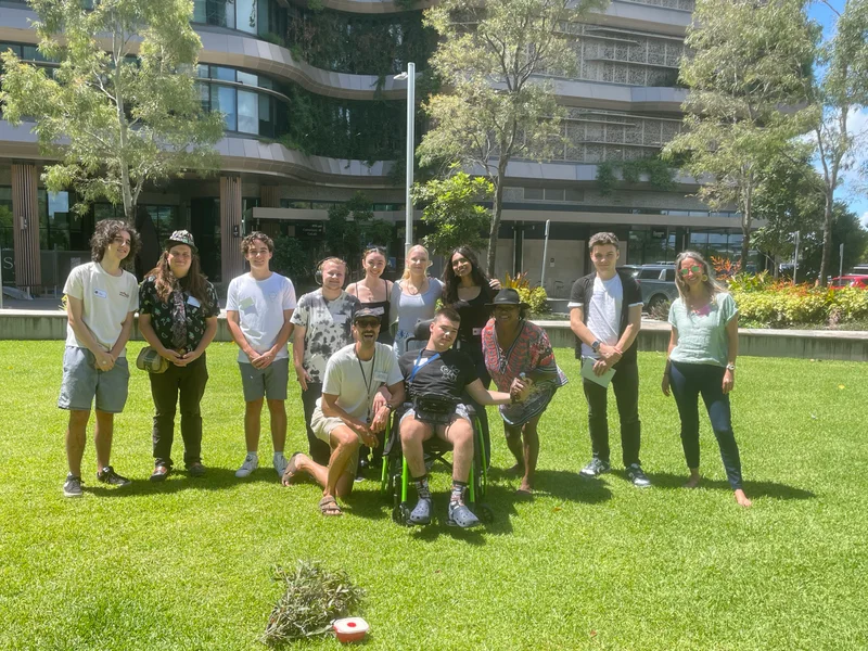 A group of young Sunshine Coast locals stand in front of Sunshine Coast Council's City Hall on the grass lawn.