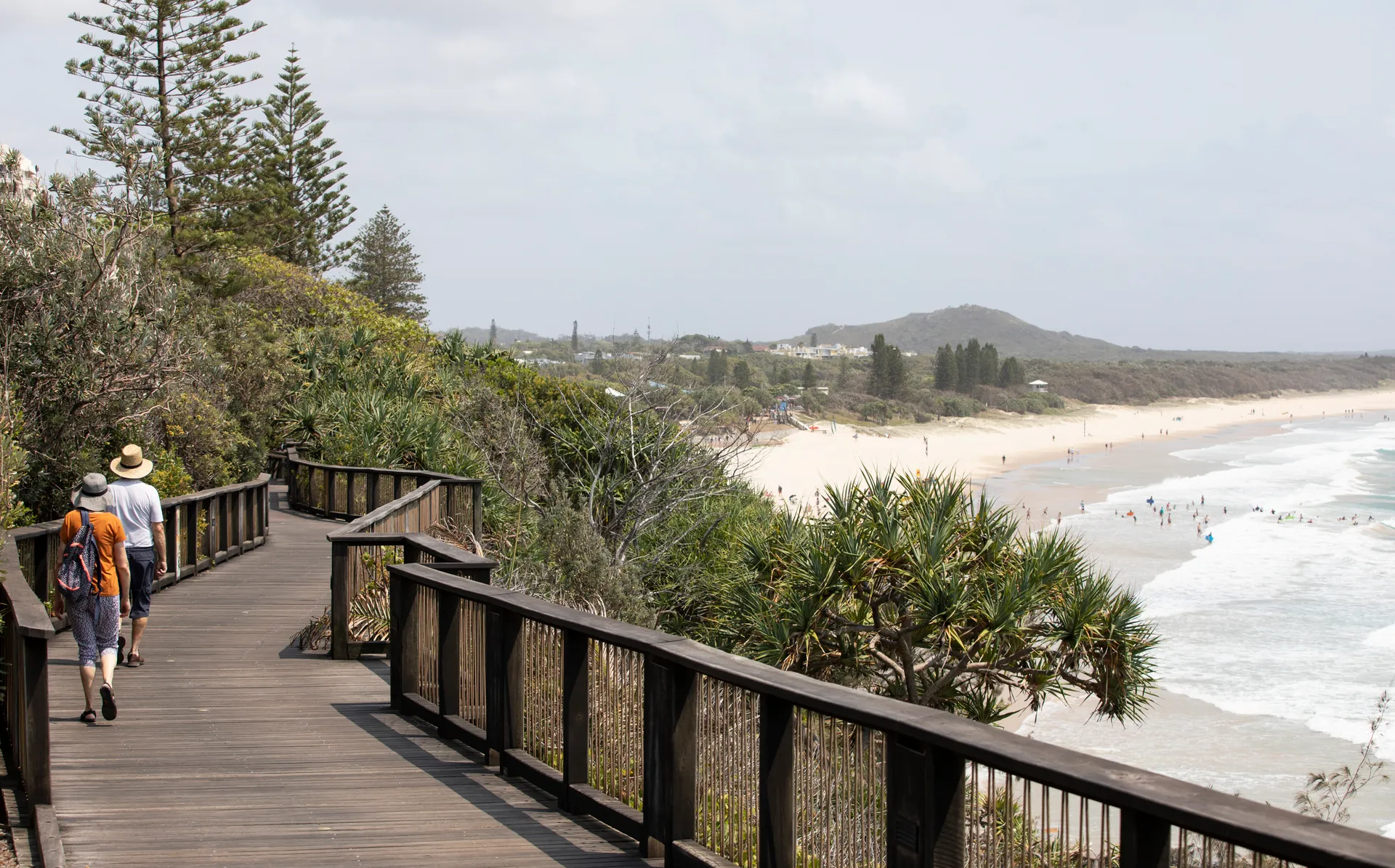 People walk along the coastal boardwalk at Coolum Beach.