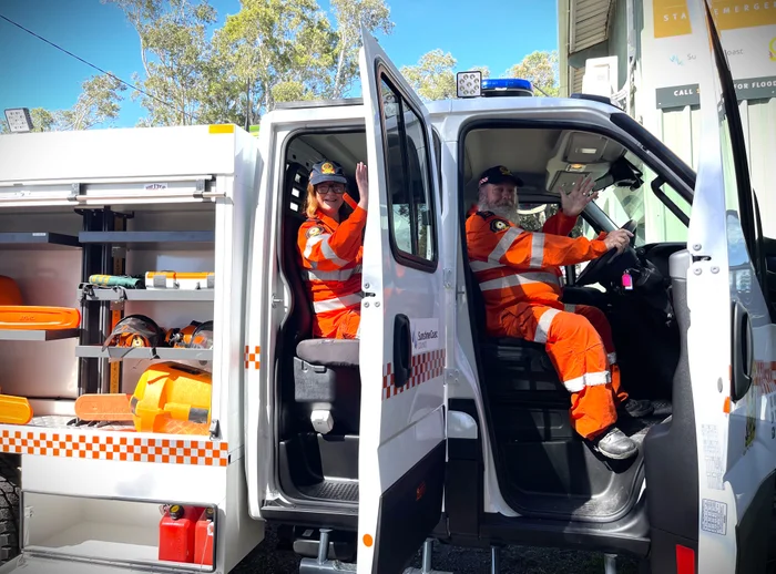 Two SES volunteers' wave from inside the new SES vehicle.