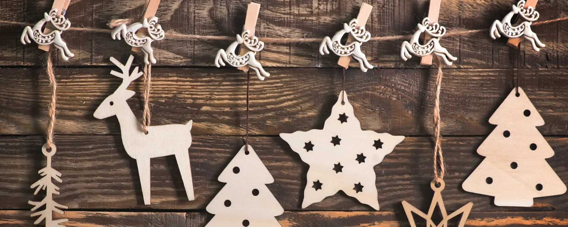 Timber Christmas decorations hanging against a wooden plank wall