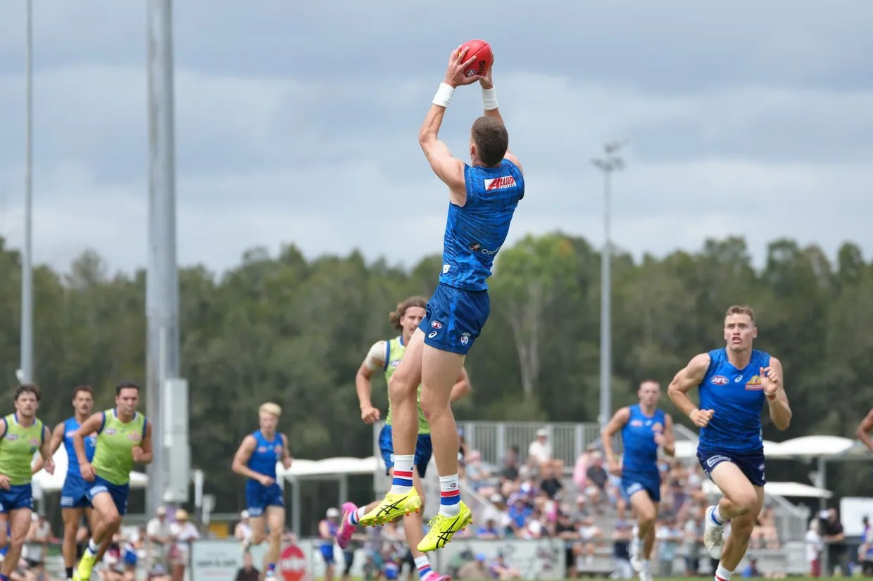 An AFL player jumping up to catch the ball