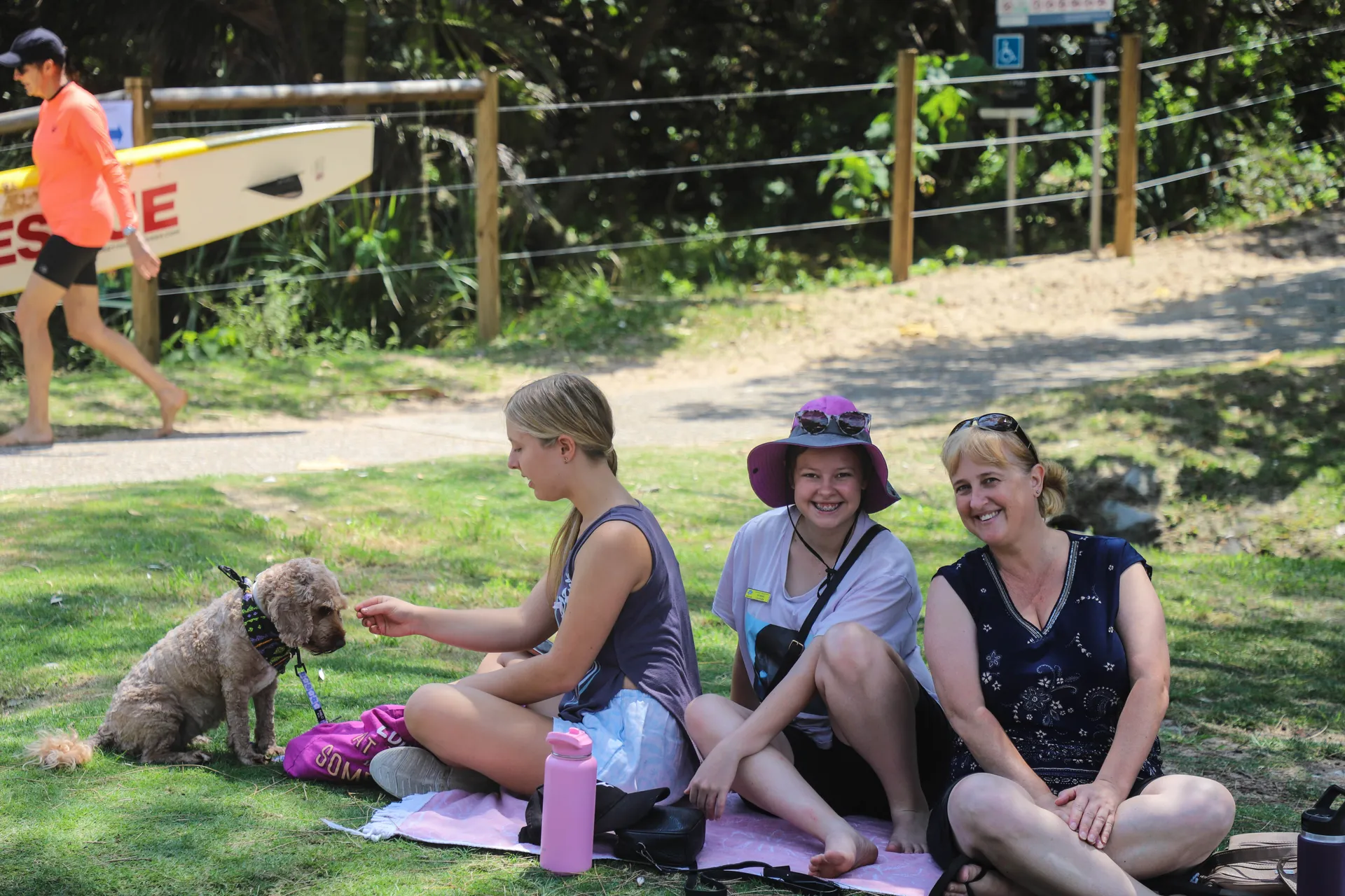 Three people sitting on a rug in the park.