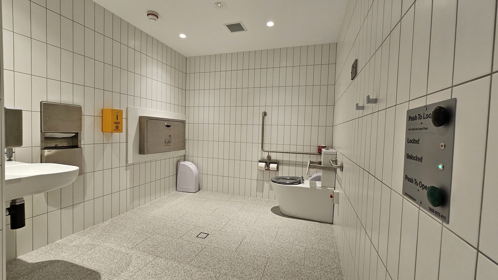 Altitude Nine amenities - toilet, sink, baby change station with signage and buttons on the wall for exit