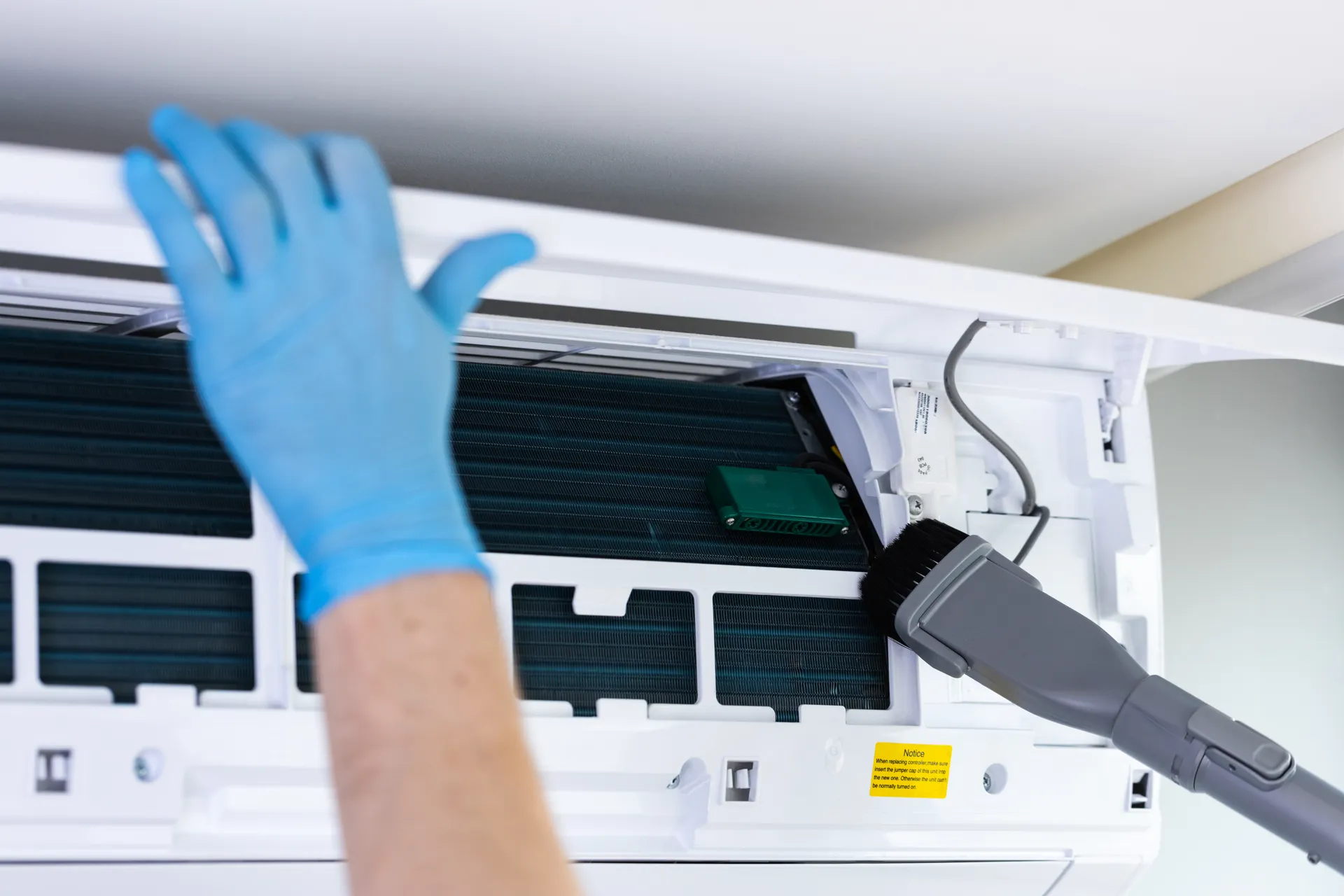 split system unit being cleaned with soft vacuum brush