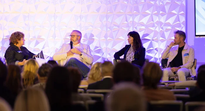 A panel of four people sit on a stage.