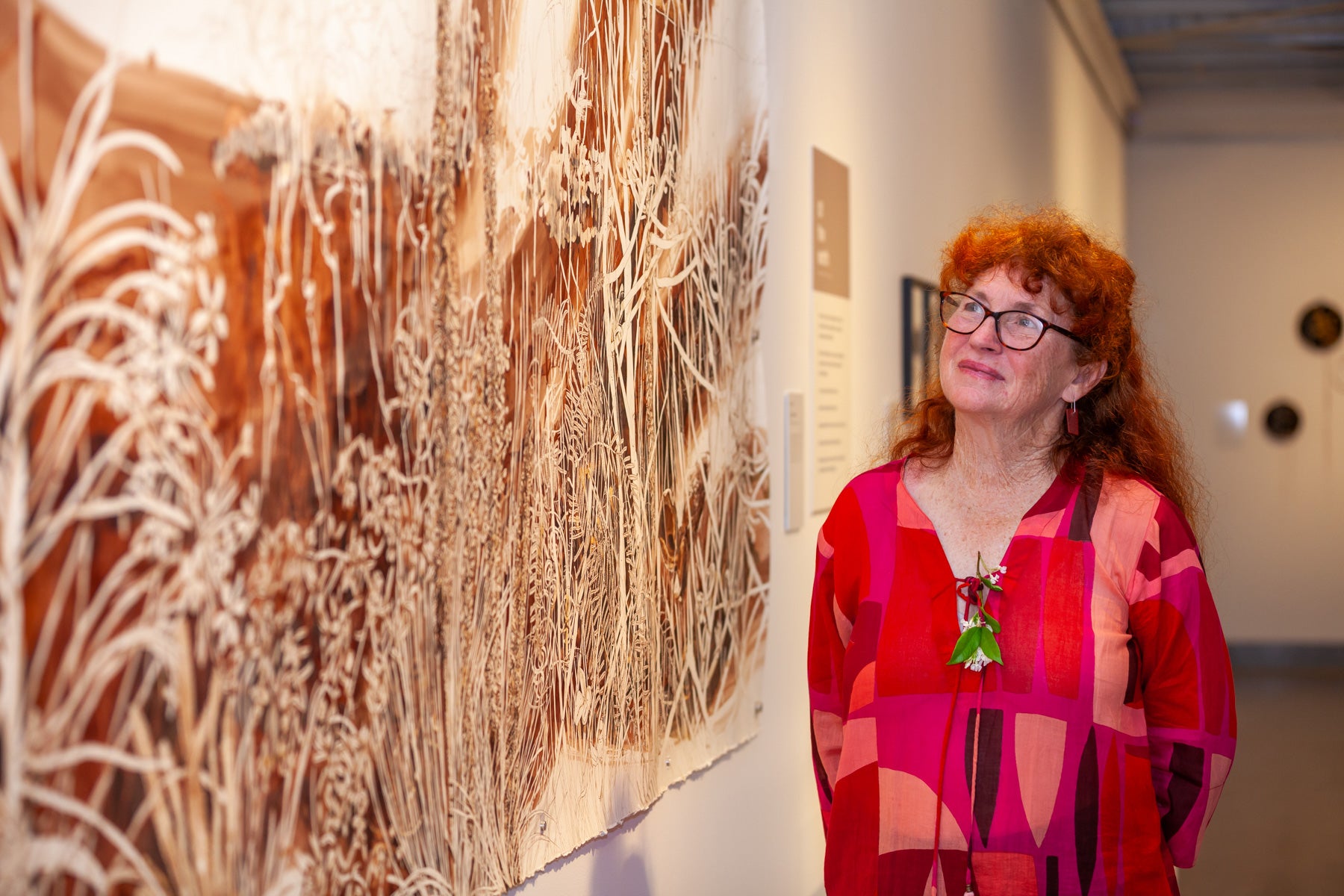 A woman admiring an artwork at the Wildflowering by Design exhibition launch