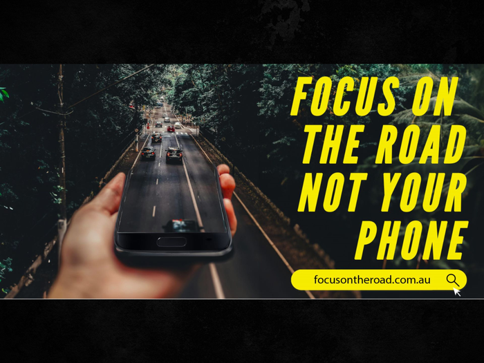 Bright yellow words 'Focus on the road not your phone' campaign. Images show a large hand holding a black mobile phone over a road with cars driving from it. 