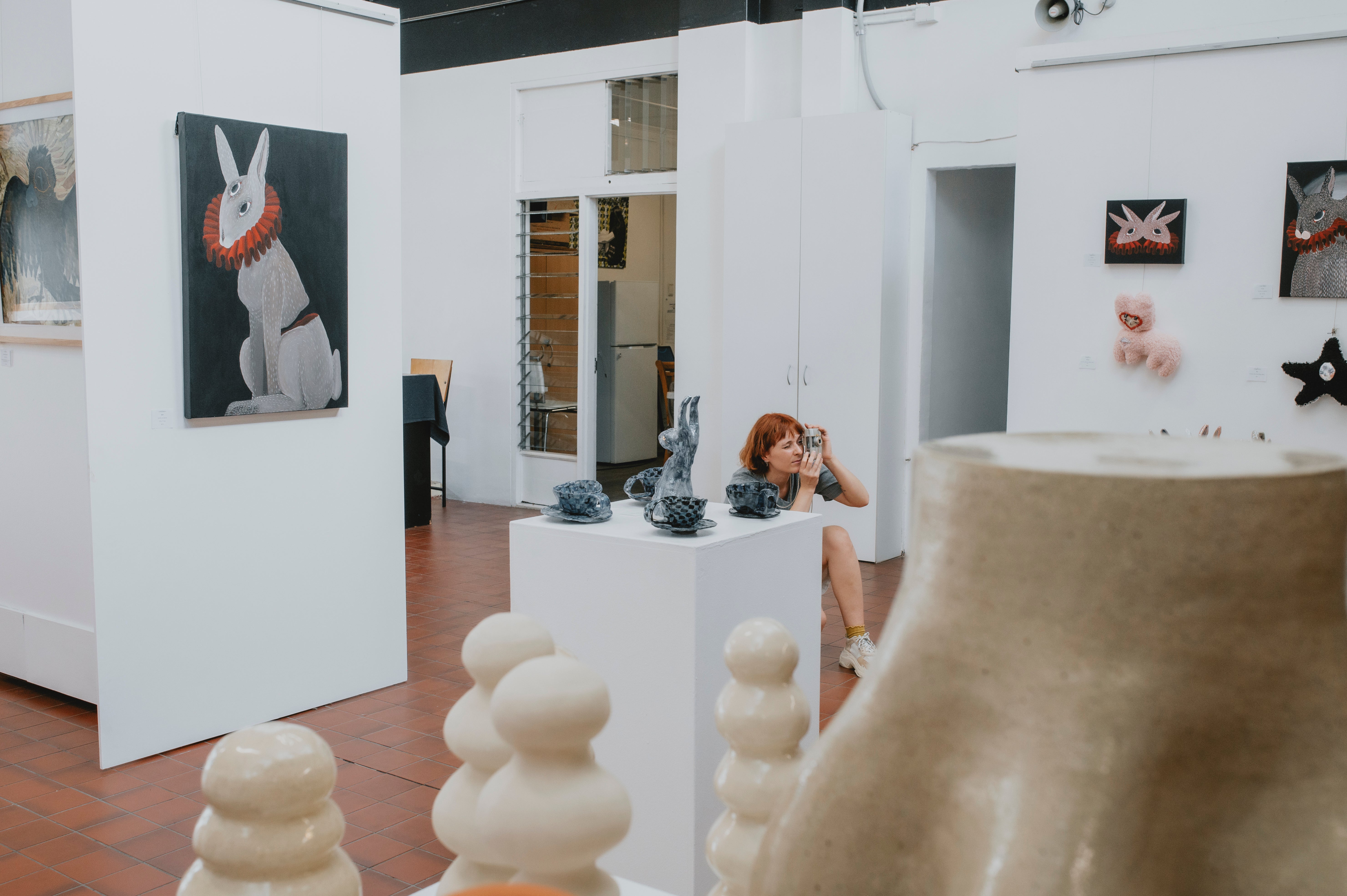 Lady taking a photo in art gallery with white walls - Image by Cooper Brady Photography