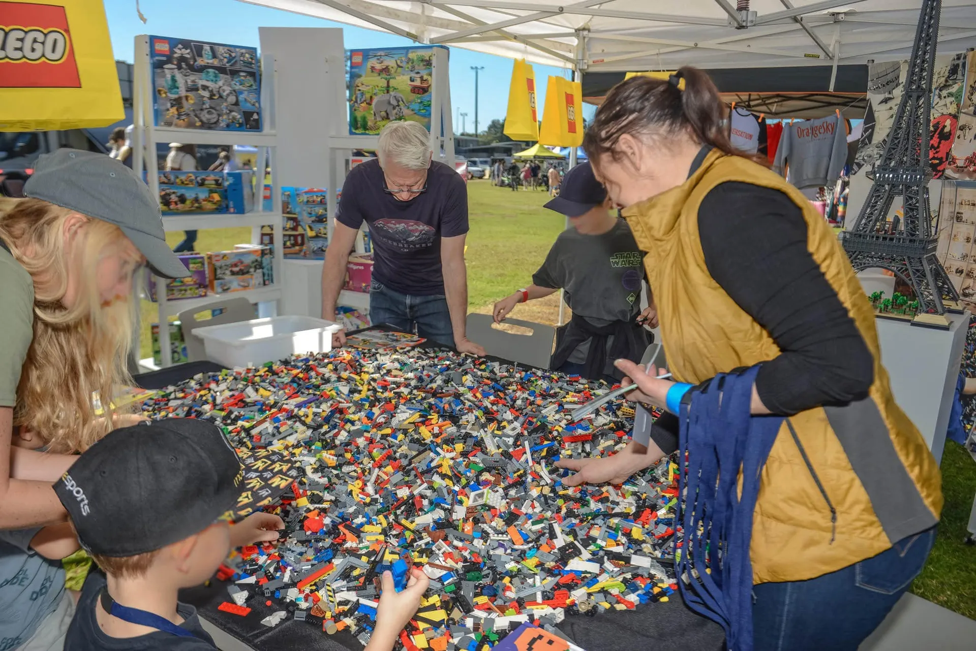 5 people (kids and adults) huddled over a huge table of lego pieces.