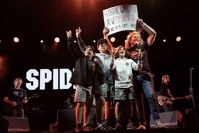 Wave Raiders band members with Kram from Spiderbait with the sign they were holding in the moshpit: "SPIDERBAIT, WE ❤ U! CAN WE PLAY CALYPSO WITH U, WE ARE IN A KID'S BAND