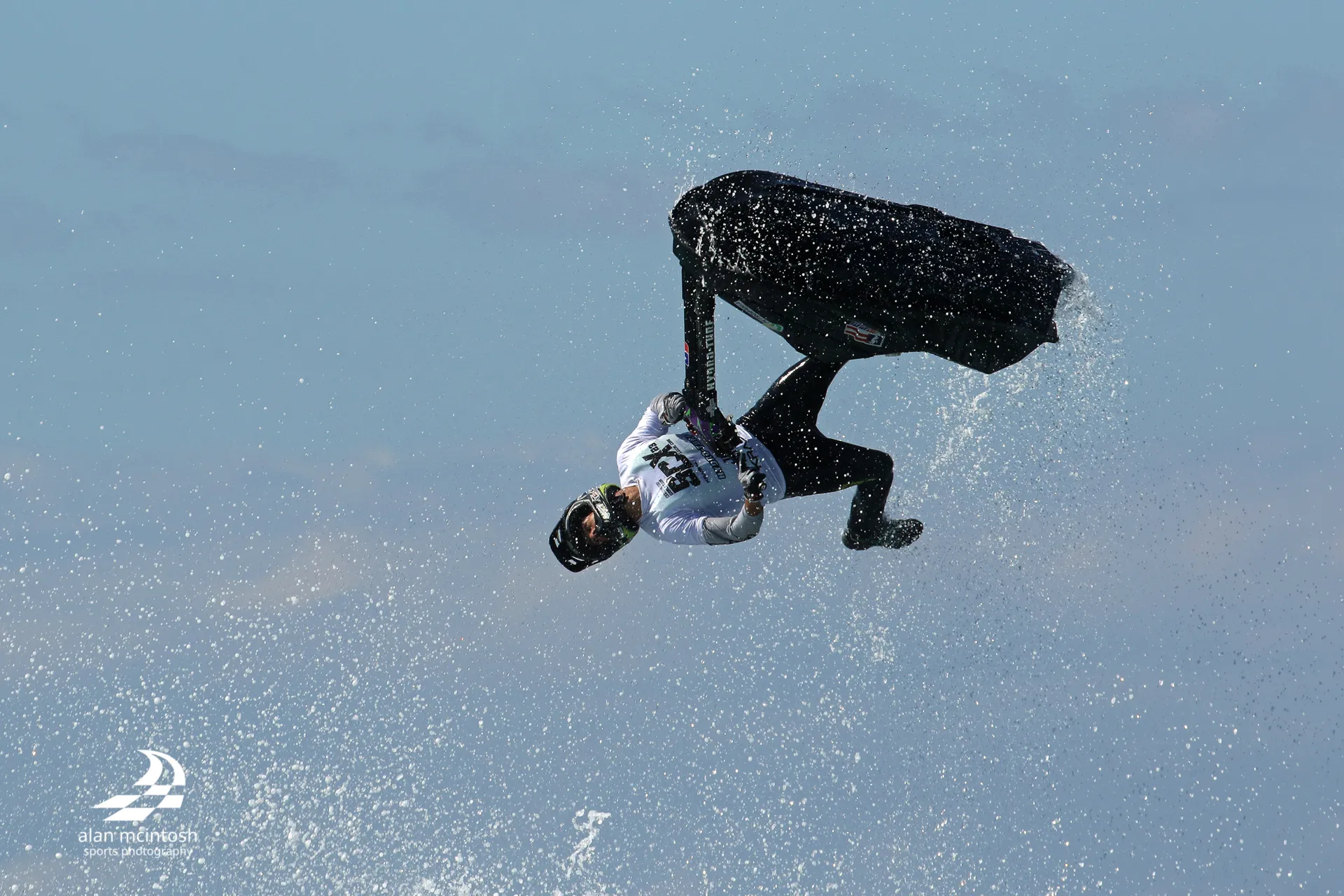 A jetski rider up in the air - flipping upside down and kicking his leg out