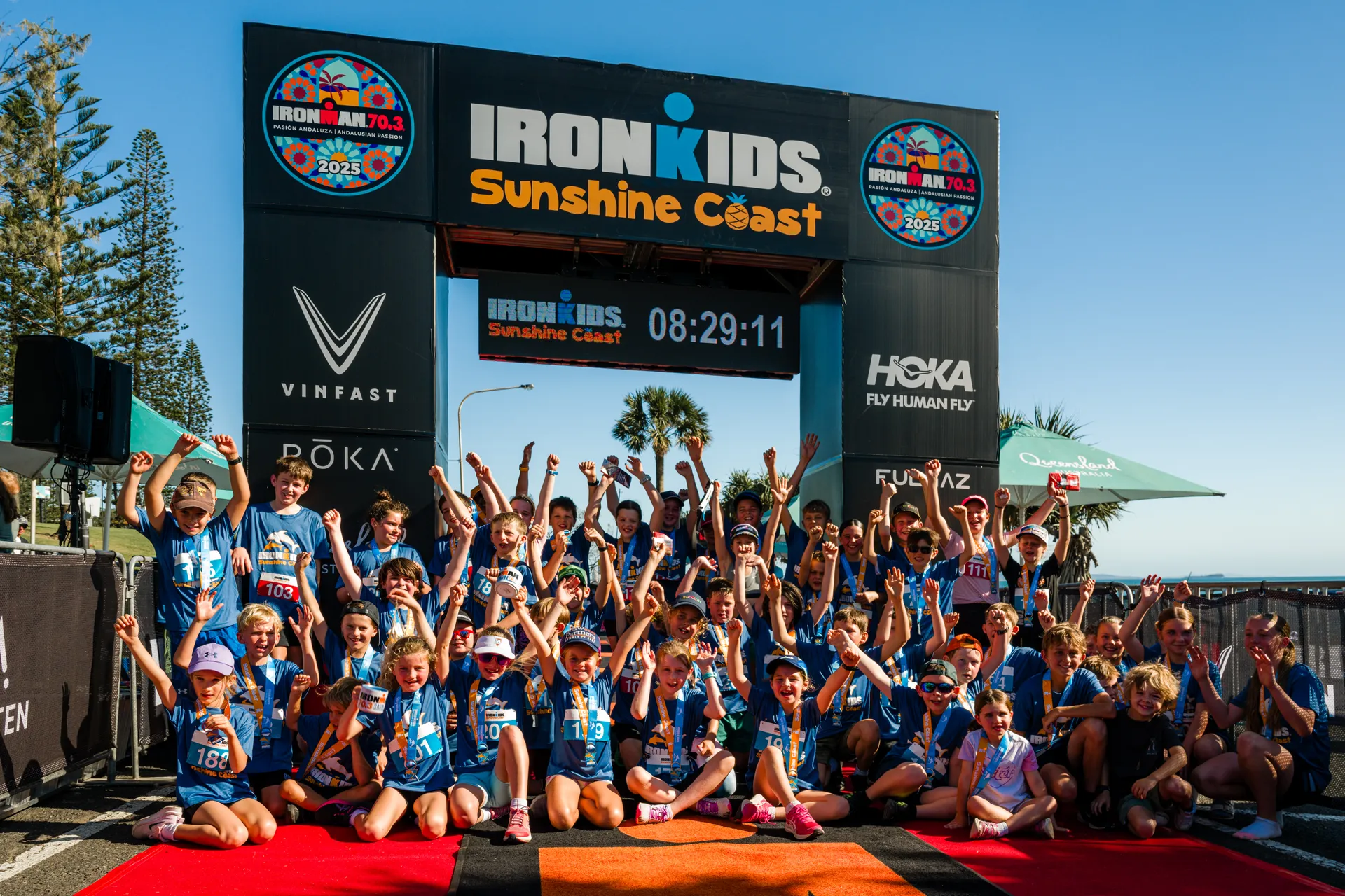 A group picture of IRONMAN kids at the finish line with their arms up in the air!