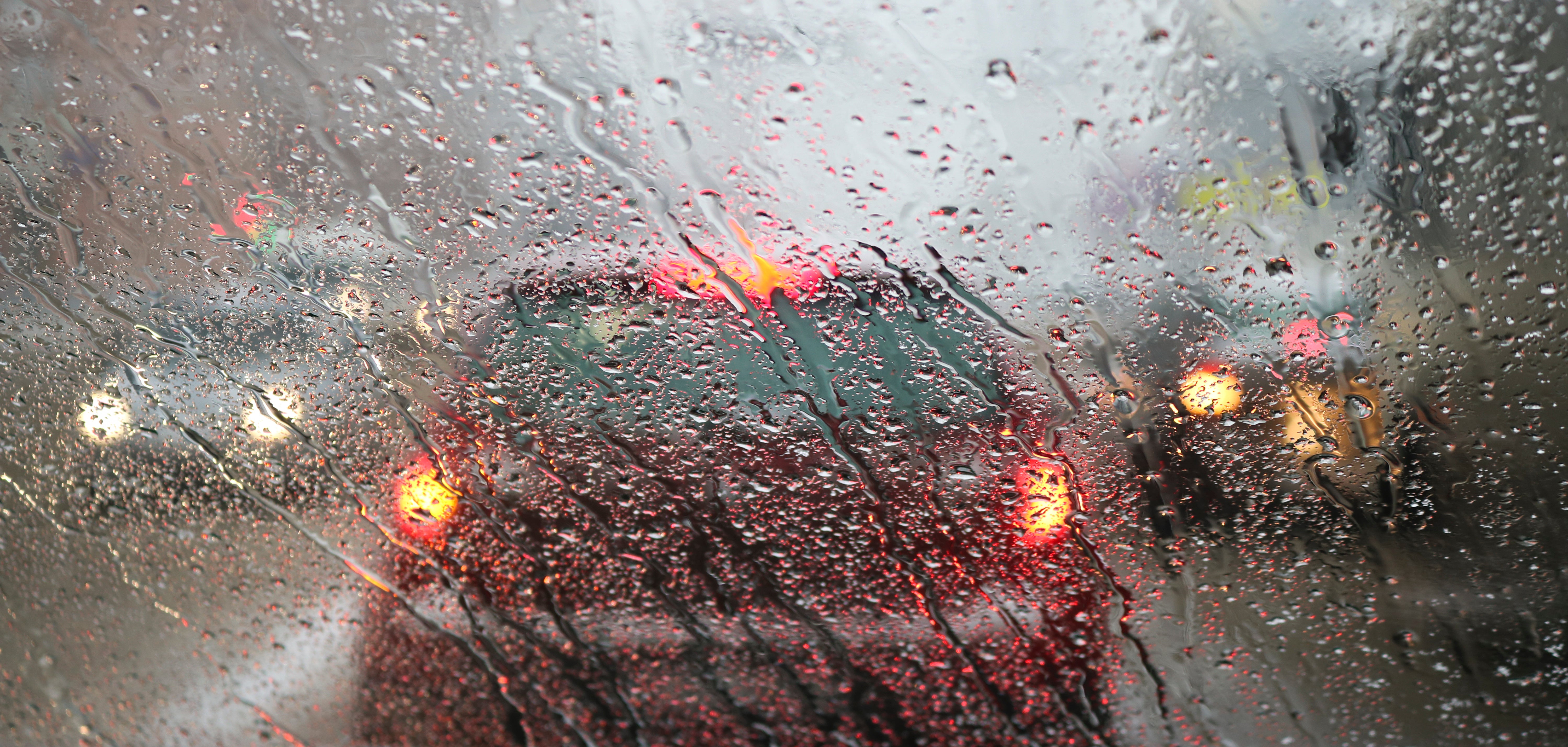 windscreen of a car with rain pouring down and traffic in front