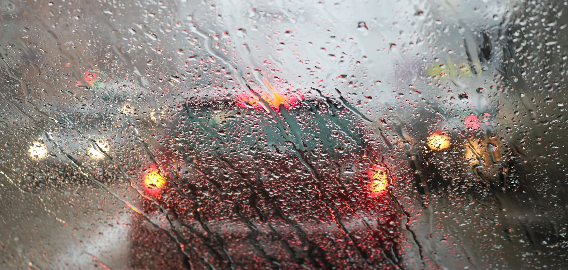 windscreen of a car with rain pouring down and traffic in front