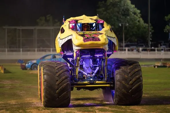 A front on view of a yellow and purple monster truck.