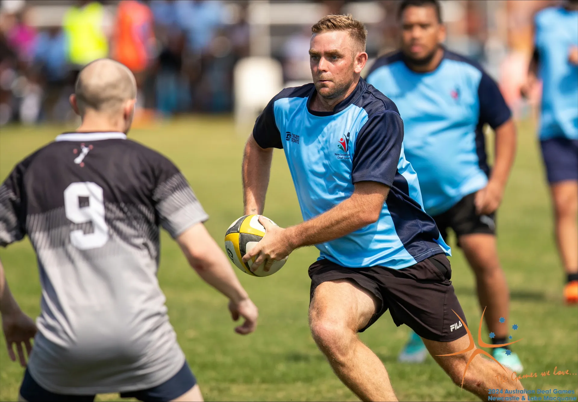 Two touch football players - one with his back to us (with the number nine on his shirt) and one man running fowards holding the ball and moving to side step.