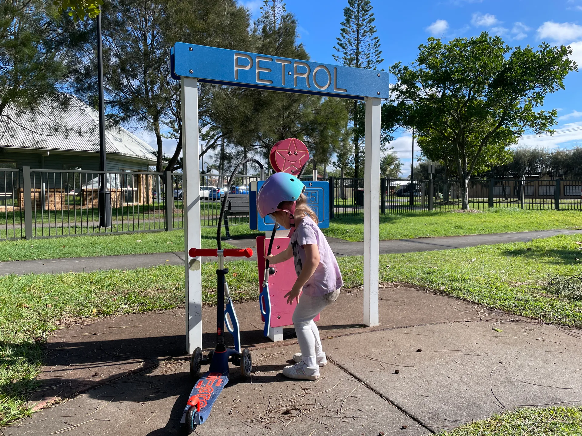 Petrol station play equipment in playground with girl on scooter