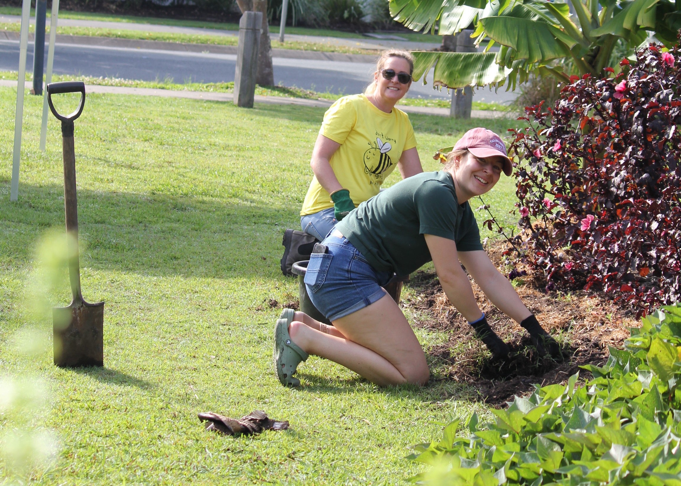 Two smiling volunteers digging tin the garden.