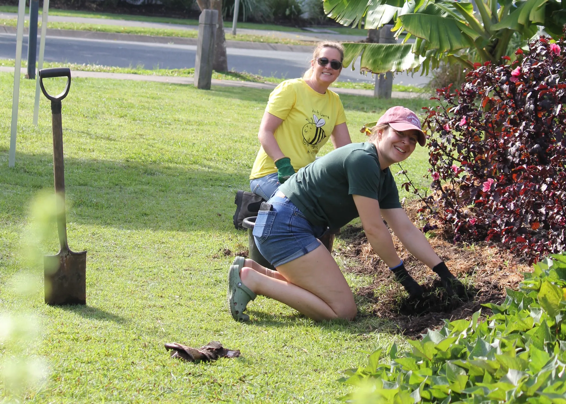 Two smiling volunteers digging tin the garden.