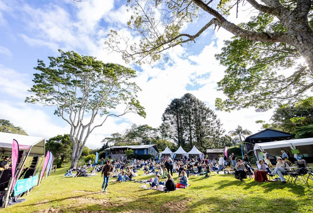 A landscape view of festival guests gathered on the hill for live music and entertainment on stage.