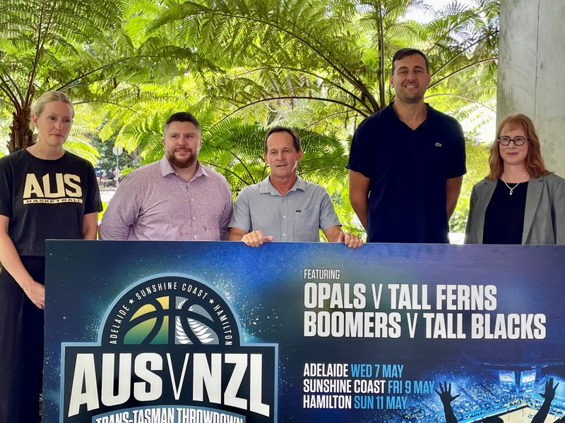 Trish Fallon (Basketball Australia), Sunshine Coast Cr Terry Landsberg, Todd Flahey (Basketball Qld), Fiona Allen (Basketball Qld), Andrew Bogut (Boomers) standing behind a sign that says AUS v NZL featuring 
Opals V Tall Ferns
Boombers v Tall Blacks
Adelaide WED 7 MAY
Sunshine Coast FRI 9 MAY
Hamilton SUN 11 MAY