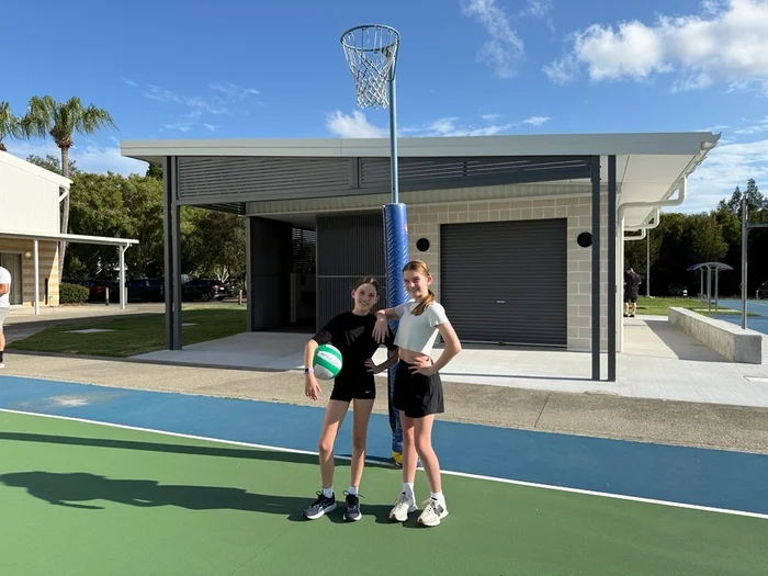 Young girls playing netball, with new Play Our Way amenities in the background, Caloundra Indoor Sports Complex