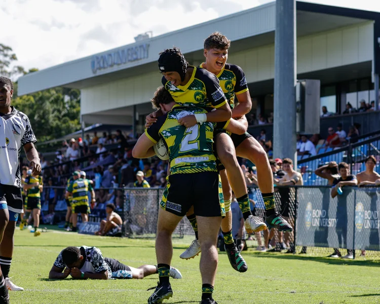 Three rugby players in a tackle.