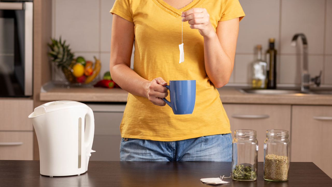 lady making tea, dipping a tea bag in a mug