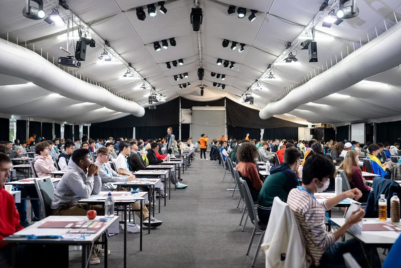An exam room set up with students sitting at desks taking part in the International Mathematics Olympiad (IMO) 2025 at Novotel Twin Waters