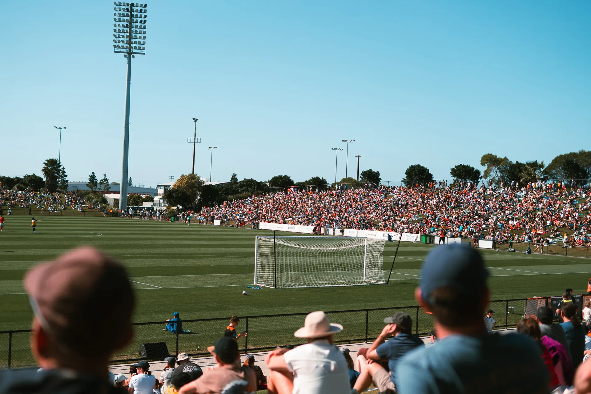 Taken from the crowd, looking towards a game of football in play with Brisbane Roar.