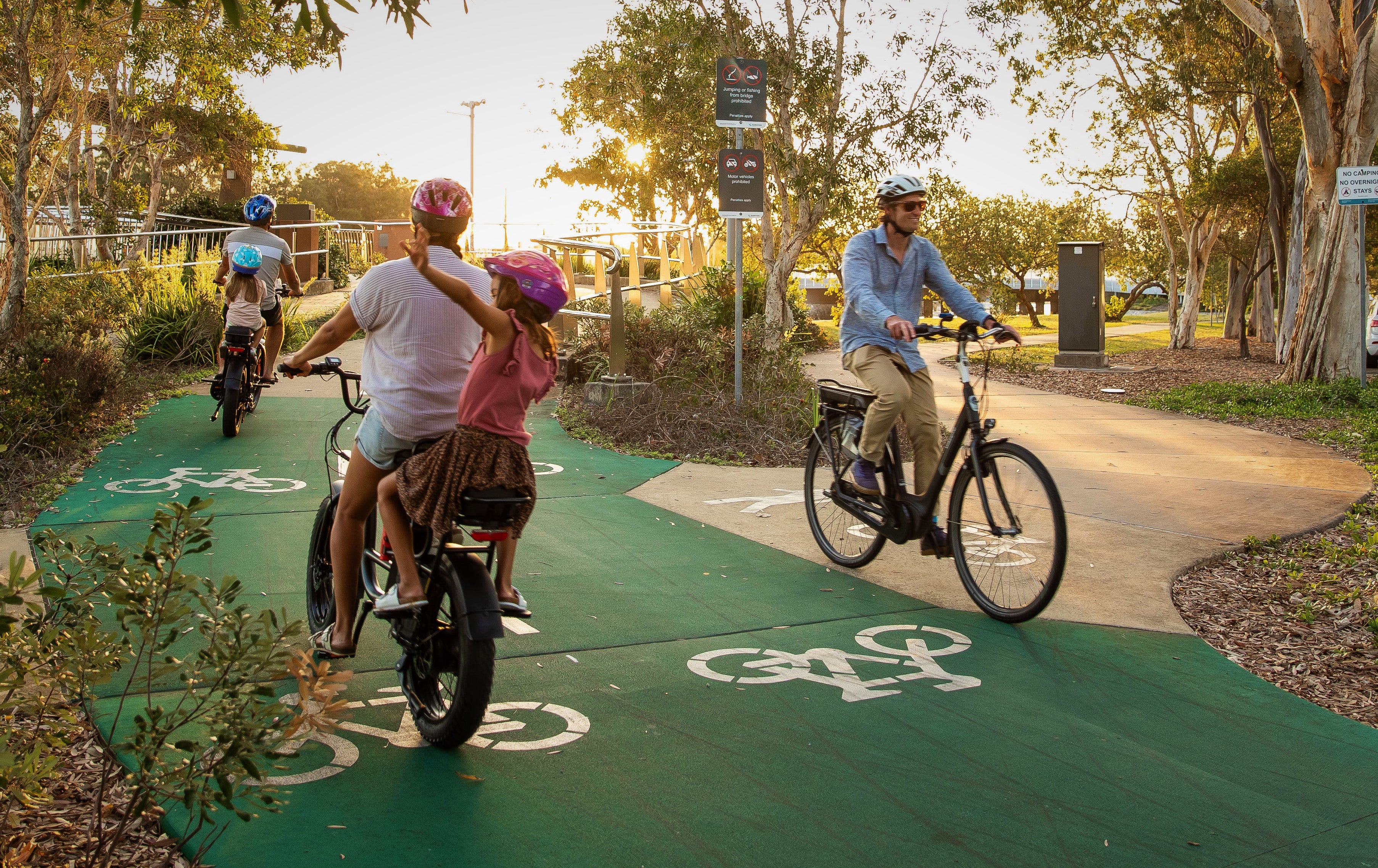 Bicycle riders going in both directions on a green bike path.
