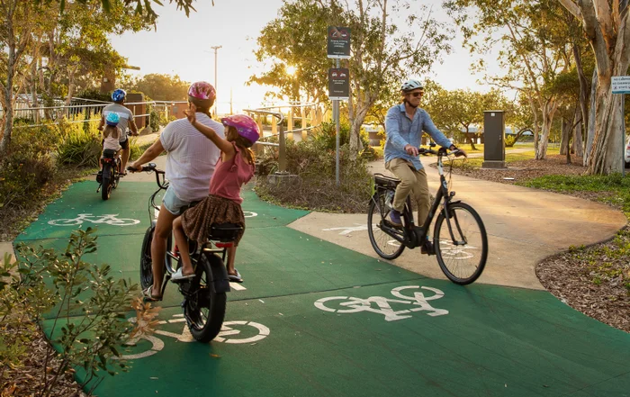 Bicycle riders going in both directions on a green bike path.