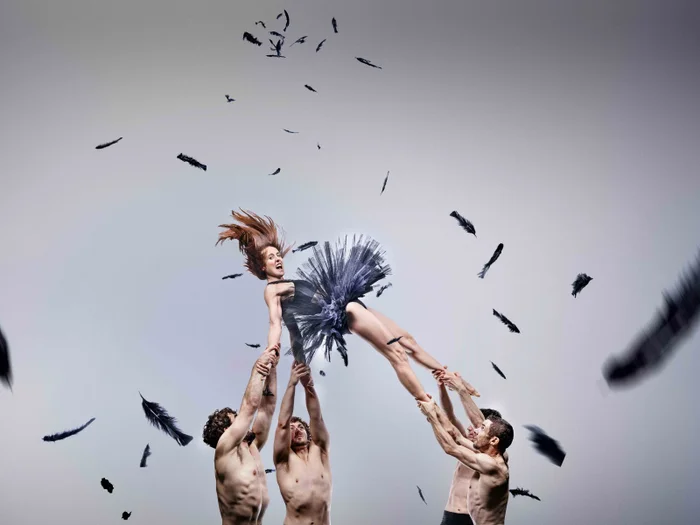Stunning ballet dancer being captured mid air by four gentlemen. 