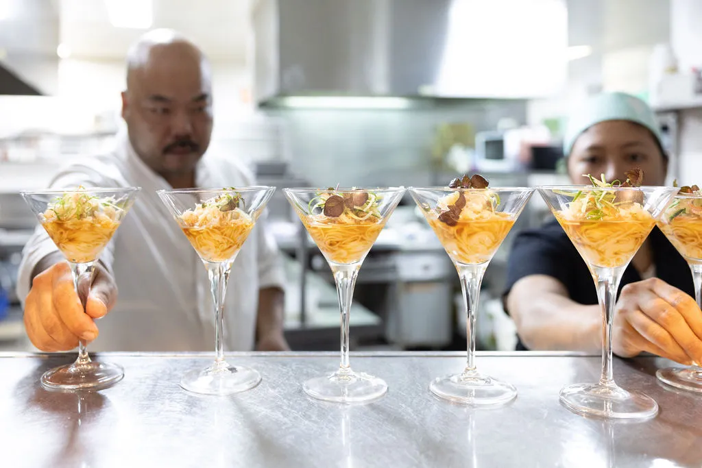 A chef at each end of the image; holding a food filled cocktail glass.